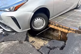Ôtô mắc kẹt do rơi xuống hố sau khi mặt đường sụp lún. (Nguồn: Kyodo)