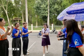 Mỗi thí sinh đến điểm thi đều nhận được tràng pháo tay động viên và những lời chúc may mắn từ các anh chị sinh viên, đoàn viên tình nguyện. (Ảnh: Hồng Giang/TTXVN)