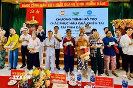 Trao tiền, quà hỗ trợ người dân vùng lũ. (Ảnh: CTV/TTXVN)