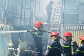 Cảnh sát tiến hành công tác dập lửa ngôi nhà đang cháy. (Ảnh TTXVN phát)