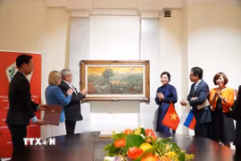 Phu nhân Ngô Phương Ly tặng bức tranh “Những đồi cọ” của cố họa sỹ Phan Kế An. (Ảnh: Tâm Hằng/TTXVN)