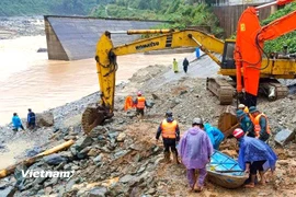 Phối hợp máy xúc và xuồng máy khẩn trương cứu hộ 2 người dân bị cô lập do nước lũ chia cắt. (Ảnh: PV/Vietnam+)