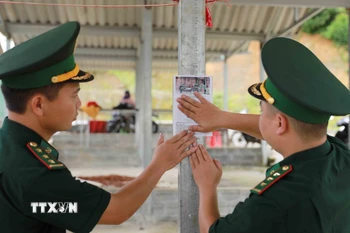 Dán mã QR tại chợ của xã Sin Suối Hồ để người dân dễ tiếp cận nhằm tố giác tội phạm tới hòm thư của đơn vị. (Ảnh: Quý Trung/TTXVN)