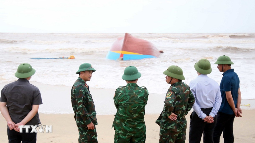 Lên phương án trục vớt tàu cá bị đánh chìm và dạt vào tại khu vực biển xã Bắc Trạch. (Ảnh: Tá Chuyên/TTXVN)