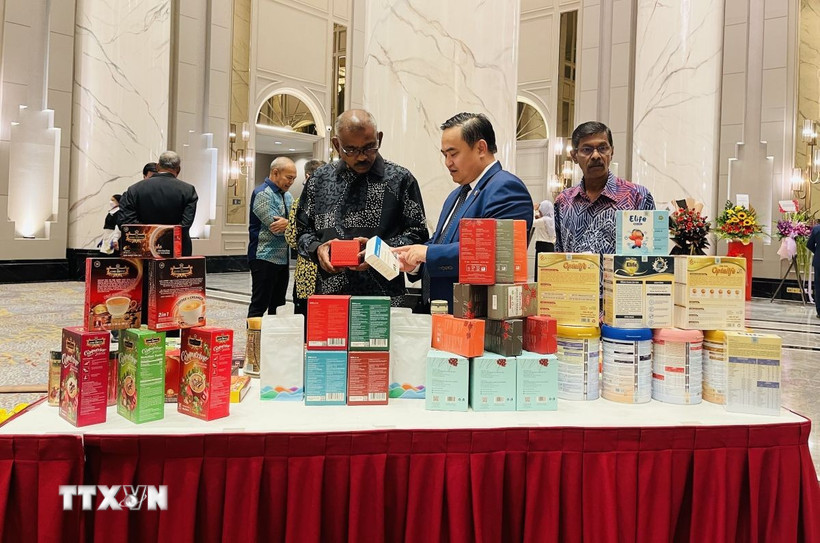 Tham tán Thương mại Việt Nam tại Malaysia Lê Phú Cường (giữa) giới thiệu với khách mời các sản phẩm truyền thống của Việt Nam. (Ảnh: Thành Trung/TTXVN)