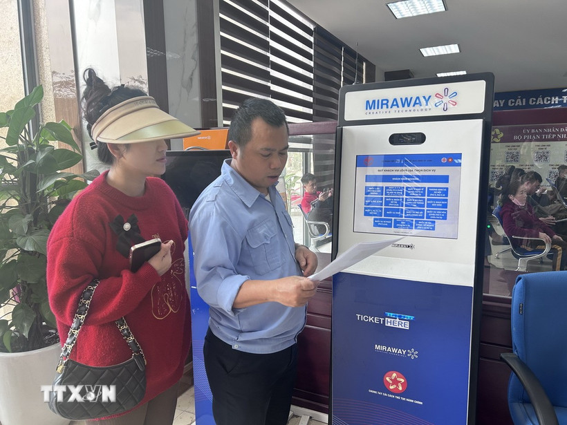 Cán bộ hướng dẫn thủ tục lấy số cho người dân tại Trung tâm Dịch vụ công Thành phố Vinh. (Ảnh: Bích Huệ/TTXVN)