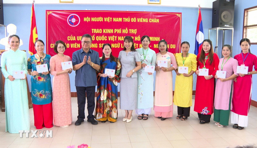 Đại diện Đại sứ quán Việt Nam tại Lào và Hội người Việt Nam thủ đô Vientiane trao quà cho các thầy cô giáo. (Ảnh: Bá Thành/TTXVN)