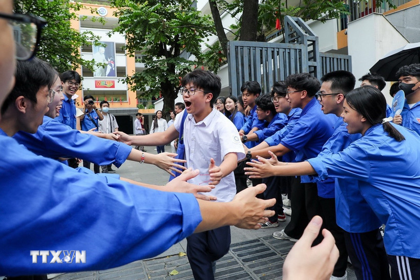 Các bạn sinh viên tình nguyện chia sẻ niềm vui và khích lệ tinh thần thí sinh tại điểm trường THCS Ngô Sĩ Liên (quận Hai Bà Trưng). (Ảnh: Khánh Hòa/TTXVN_