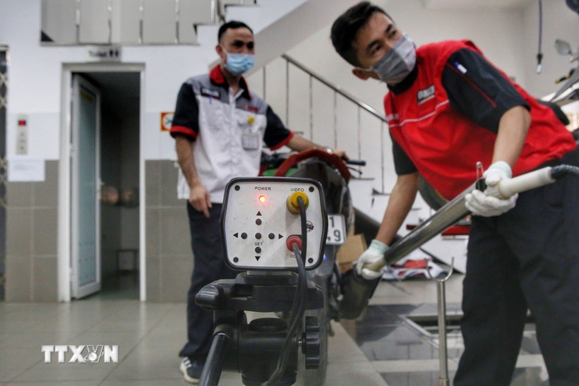 Các nhân viên kiểm tra khí thải xe máy. (Ảnh: Tuấn Đức/TTXVN)