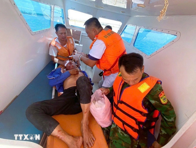 Chiến sỹ Đồn Biên phòng Diễn Thành và quân y sơ cứu ban đầu cho nạn nhân ngay trên biển và đưa nạn nhân vào bờ an toàn. (Ảnh: TTXVN phát)