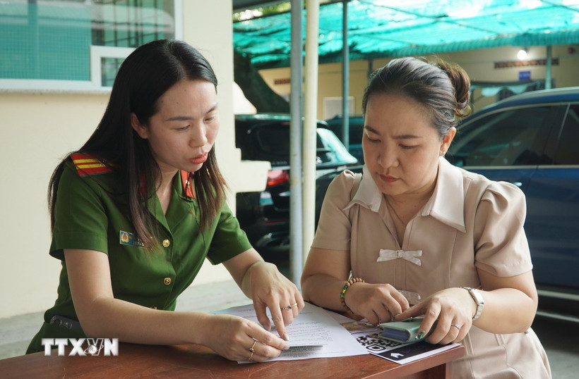 Cán bộ Công an hướng dẫn làm thủ tục cho người dân. (Ảnh: Trung Tuyến/TTXVN)