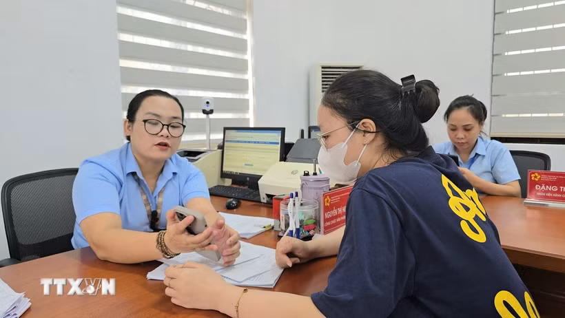 Công chức phường Mạo Khê, Quảng Ninh, hướng dẫn công dân nộp hồ sơ chứng thực lên Cổng dịch vụ công Quốc gia. (Ảnh: Thanh Vân/TTXVN)