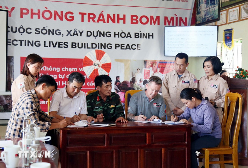 Các bên ký bàn giao và tiếp nhận diện tích đất sạch bom mìn tại xã Hoàn Lão (Quảng Trị). (Ảnh: Tá Chuyên/TTXVN)
