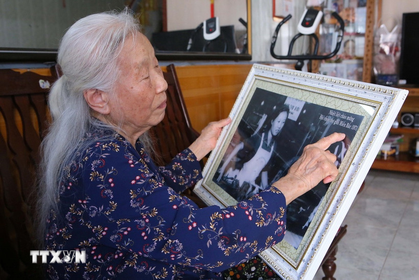 Bà Vũ Thị Bích Liên cùng tấm ảnh chụp khi bà giành được giải Nhất cuộc thi “Hội chọn thợ giỏi miền Bắc,” năm 1971. (Ảnh: Công Luật/TTXVN)