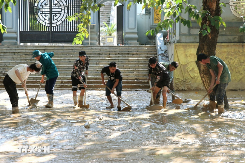 Người dân dọn bùn đất trên các tuyến đường ở phường Hà Giang 1 (Tuyên Quang). (Ảnh: Đức Thọ/TTXVN)