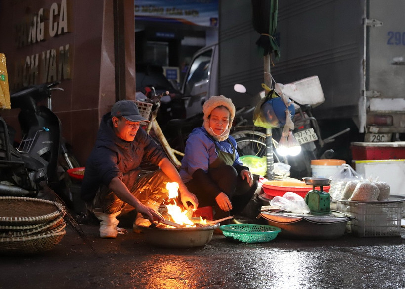 Người dân, tiểu thương đi chợ sớm đốt lửa để sưởi ấm. (Ảnh: Xuân Tiến/TTXVN)