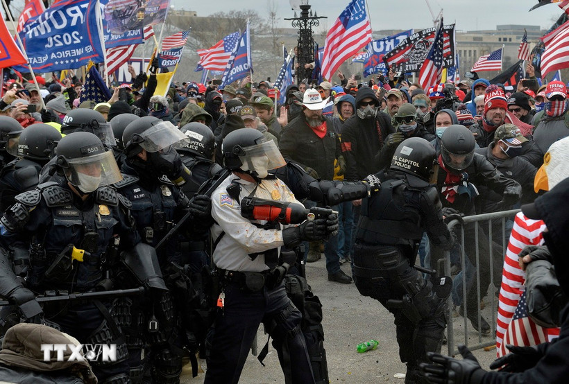 Người biểu tình xung đột với cảnh sát chống bạo động tại Đồi Capitol ở Washington DC., ngày 6/1/2021. (Ảnh: AFP/TTXVN)