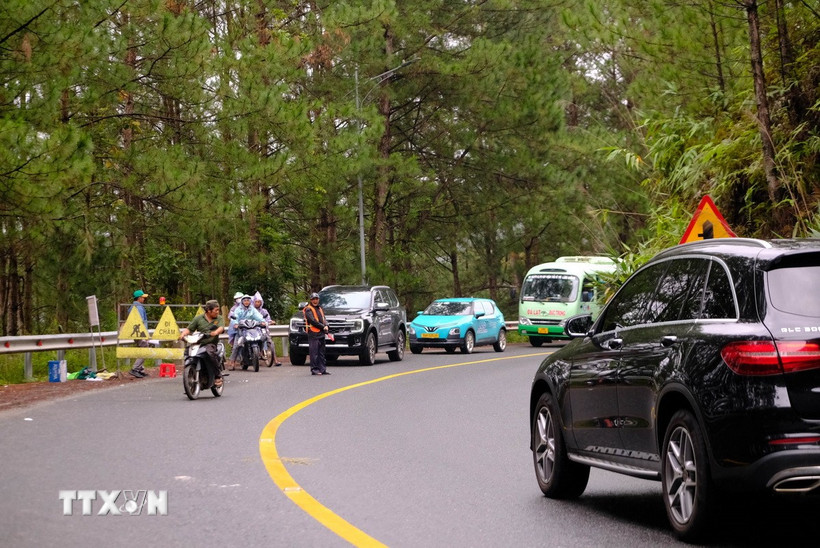 Cùng với việc thi công khắc phục sự cố, Ban Bảo trì đường bộ tỉnh Lâm Đồng và đơn vị thi công cũng tổ chức phân luồng, hướng dẫn các phương tiện luân phiên di chuyển qua đoạn đường đang bị sụt lún, sạt lở. (Ảnh: Nguyễn Dũng/TTXVN)