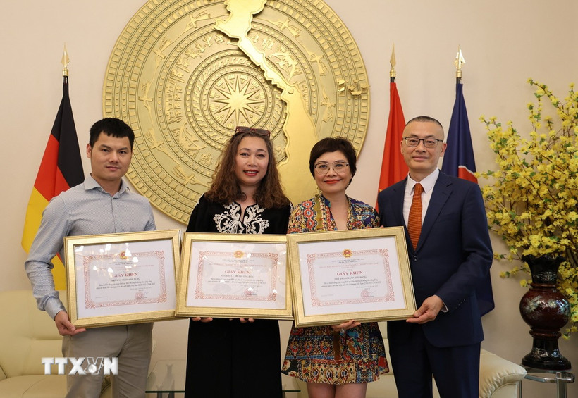 Đại sứ Vũ Quang Minh trao Giấy khen cho các phóng viên thường trú TTXVN tại Berlin. (Ảnh: PV TTXVN tại Đức)