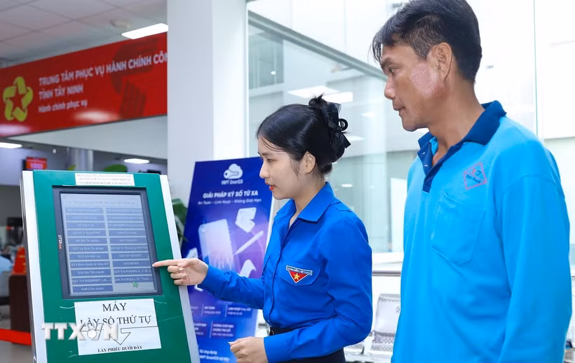 Thanh niên tình nguyện hướng dẫn người dân lấy số thứ tự tại Trung tâm phục vụ Hành chính công tỉnh Tây Ninh. (Ảnh: Thành Phương/TTXVN)