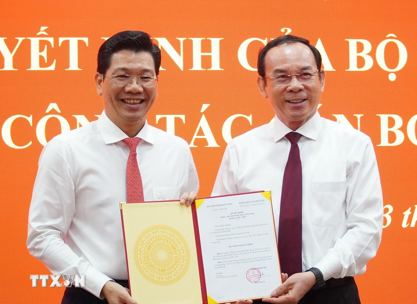 Bí thư Thành ủy Thành phố Hồ Chí Minh Nguyễn Văn Nên (bìa phải) trao Quyết định của Bộ Chính trị cho ông Nguyễn Mạnh Hùng. (Ảnh: Thanh Tân/TTXVN)