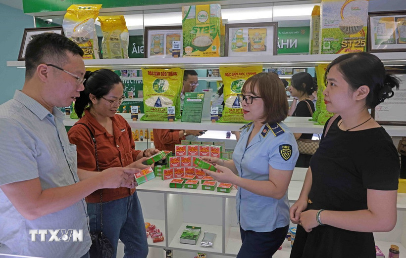 Lực lượng Quản lý thị trường hướng dẫn người dân nhận biết hàng thật, hàng giả. (Ảnh: Trần Việt/TTXVN)