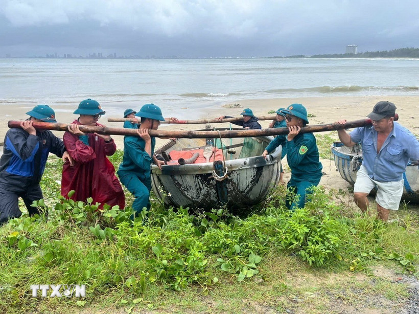 Lực lượng chức năng phường Hải Vân giúp ngư dân đưa thuyền thúng lên bờ tránh bão. (Ảnh: TTXVN phát)