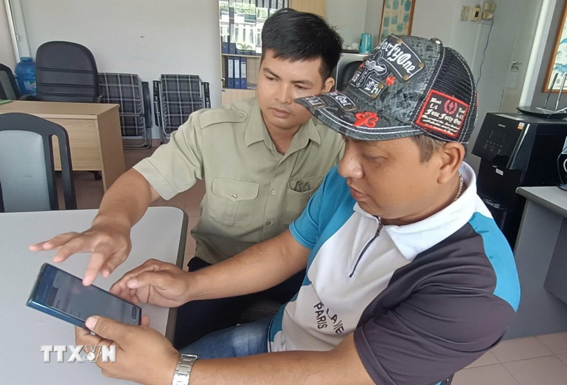 Nhân viên Văn phòng kiểm tra, kiểm soát nghề cá cảng Cát Lở, phường Phước Thắng, Thành phố Hồ Chí Minh hướng dẫn chủ tàu cá làm thủ tục xuất bến điện tử 2. (Ảnh: Hoàng Nhị - TTXVN)