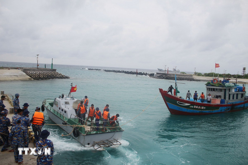 Xuồng cứu hộ của đảo Song Tử Tây (bên trái) đang lai kéo tàu cá QNg 96318-TS vào âu tàu. (Ảnh: TTXVN phát)