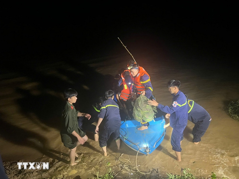 Các lực lượng chức năng cứu hộ thành công 6 người dân bị cô lập vì nước lũ đến nơi an toàn trong đêm. (Ảnh: TTXVN phát)