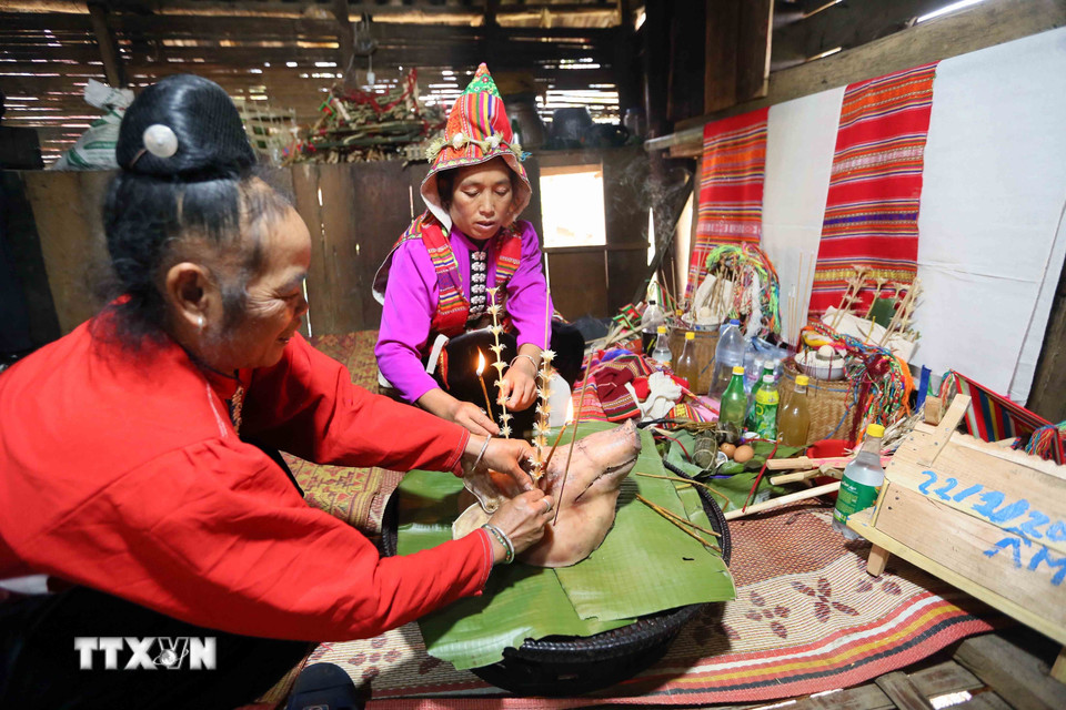 Bà Vì Thị Liên (phải), xã Phiêng Pằn, huyện Mai Sơn (tỉnh Sơn La), là thầy mo được đỡ đầu chuẩn bị lễ vật thực hiện nghi lễ Mạng Ma. (Ảnh: Quang Quyết/TTXVN)