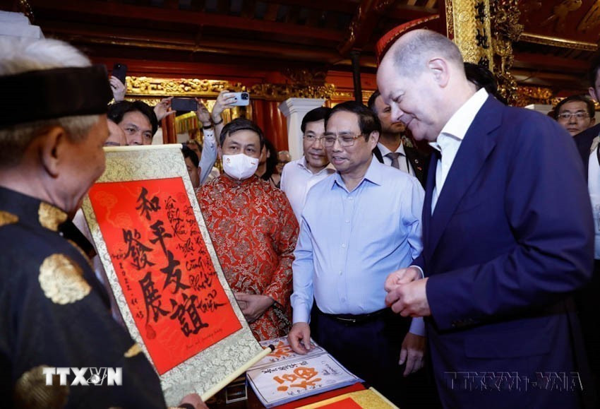 Thủ tướng Phạm Minh Chính giới thiệu bức thư pháp tới Thủ tướng Đức Olaf Scholz pháp với nội dung "Hòa bình-hữu nghị cùng phát triển," tại đền Ngọc Sơn (Hà Nội, 13/11/2022). (Ảnh: An Đăng/TTXVN)