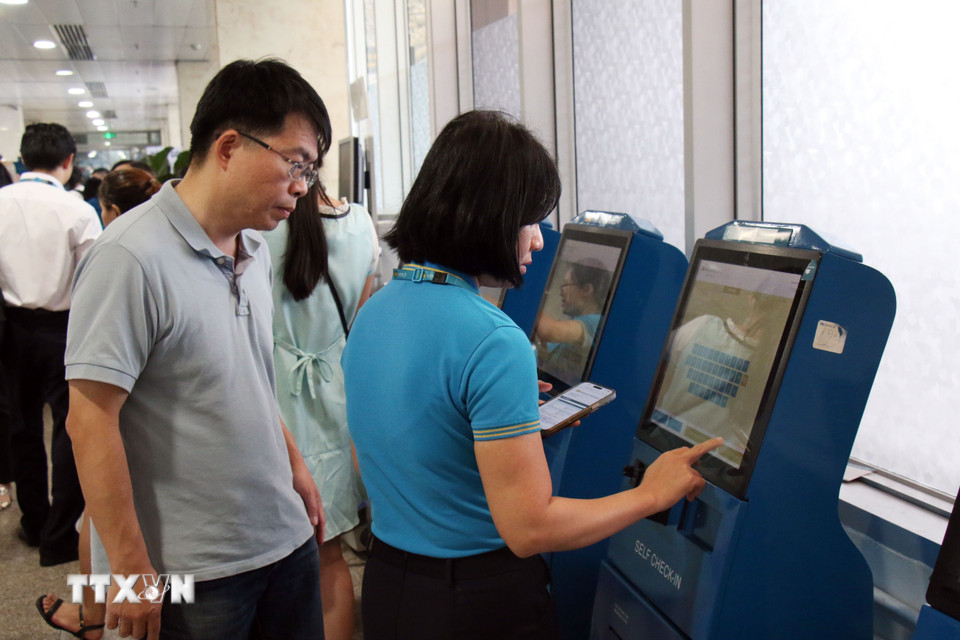 Nhân viên hỗ trợ hành khách checkin online. (Ảnh: Tiến Lực/TTXVN)