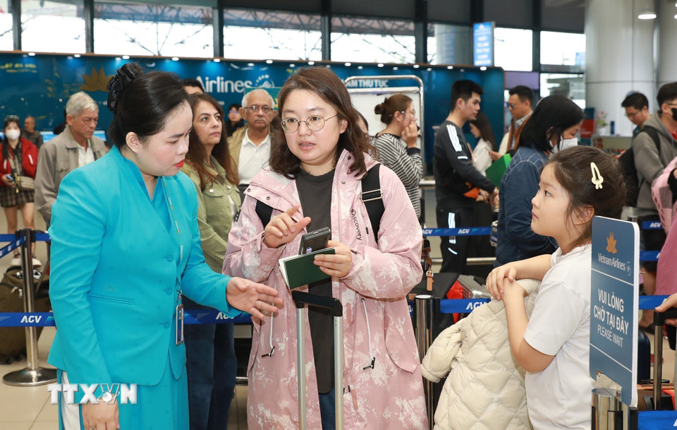 Hướng dẫn viên của Vietnam Airlines hướng dẫn người dân, du khách làm thủ tục check-in vé điện tử. (Ảnh: Quốc Khánh/TTXVN)