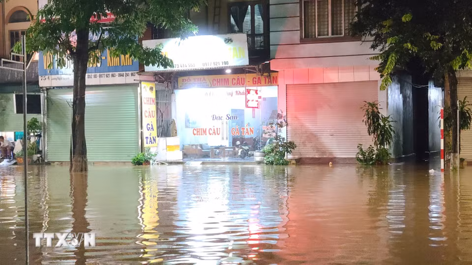 Nước ngập úng tràn vào nhà dân ven đường. (Ảnh: Trần Trang/TTXVN)