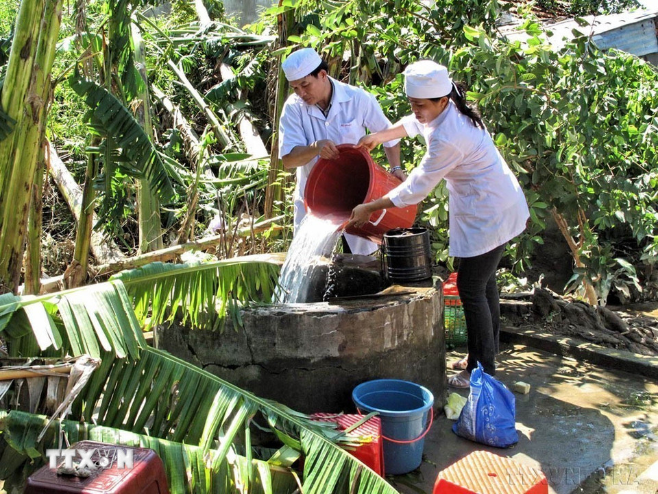 Nhân viên Trạm y tế xã Nghĩa Trung, huyện Tư Nghĩa (Quảng Ngãi) khử khuẩn nguồn nước giếng ngoài trời cho nhân dân vùng bị lụt (2009). (Ảnh: Thanh Long/TTXVN)