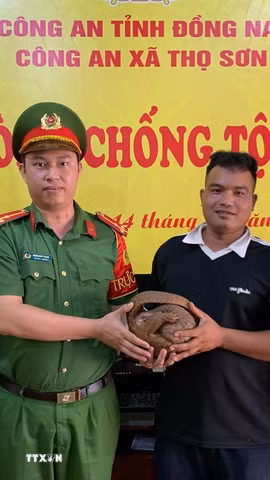 Anh Điểu Khanh (thứ 2, từ phải qua), giao nộp cá thể Tê Tê Java, có trọng lượng khoảng 3kg cho cơ quan công an xã Thọ Sơn. (Ảnh: Đậu Tất Thành/TTXVN)