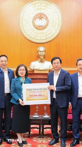 Bà Đoàn Thị Tuyết Nhung, Ủy viên Ban Thường vụ Đảng ủy, Phó Tổng giám đốc TTXVN trao ủng hộ cho đại diện Uỷ ban Trung ương Mặt trận Tổ quốc Việt Nam, ông Cao Xuân Thạo, Uỷ viên Đoàn chủ tịch, Trưởng Ban công tác Xã Hội. (Ảnh: Lê Đông/TTXVN)