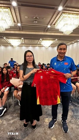 Huấn luyện viên Mai Đức Chung (phải) tặng áo thi đấu có chữ ký của các cầu thủ đội tuyển cho Tổng Lãnh sự Nguyễn Thanh Hà. (Ảnh: Thanh Tú/TTXVN)