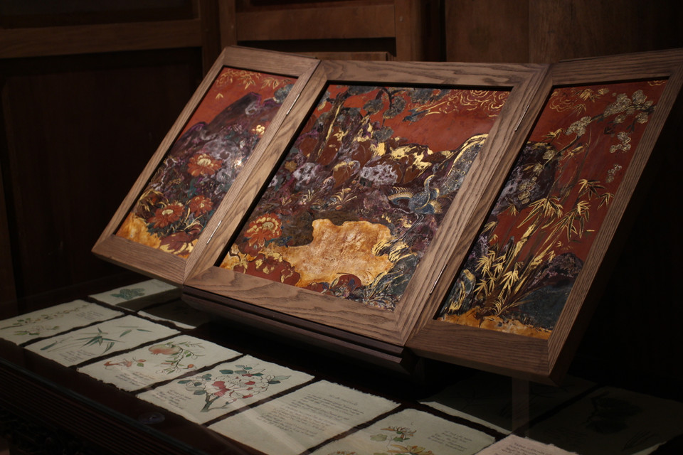 Đây là tác phẩm sách sơn mài của hai tác giả Hoài Giang và Nguyễn Trang. Họ đã ghép các loại thực vật xuất hiện trong các tranh Hàng Trống vào cùng một tác phẩm, tạo thành một khu vườn. (Ảnh: Minh Anh/Vietnam+)