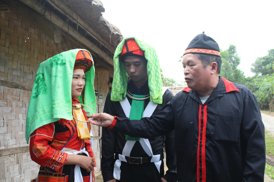 Trước lễ tái hiện, người đóng vai quan làng của làng bên nhà trai (phải) giới thiệu đôi chút cho khách tham quan có nhu cầu về trang phục của đôi trai gái Pà Thẻn, Hà Giang vào ngày cưới. Theo đó, đôi vòng bạc cô dâu đeo là do nhà gái cung cấp. Việc đeo 2 chiếc thể hiện ước mong cho đôi vợ chồng gắn kết dài lâu. Hai chiếc khăn đội đầu là để cả hai che mặt khi sau này đến ăn ở nhà nội (đối với cô dâu), nhà ngoại (đối với chú rể). Theo phong tục ngày xưa, chiếc khăn sẽ che toàn bộ khuôn mặt nhưng ngày nay, khăn chỉ che một phần cho thấy người dân đã có cải tiến trong lối suy nghĩ, ông cho biết. (Ảnh: Minh Anh/Vietnam+)