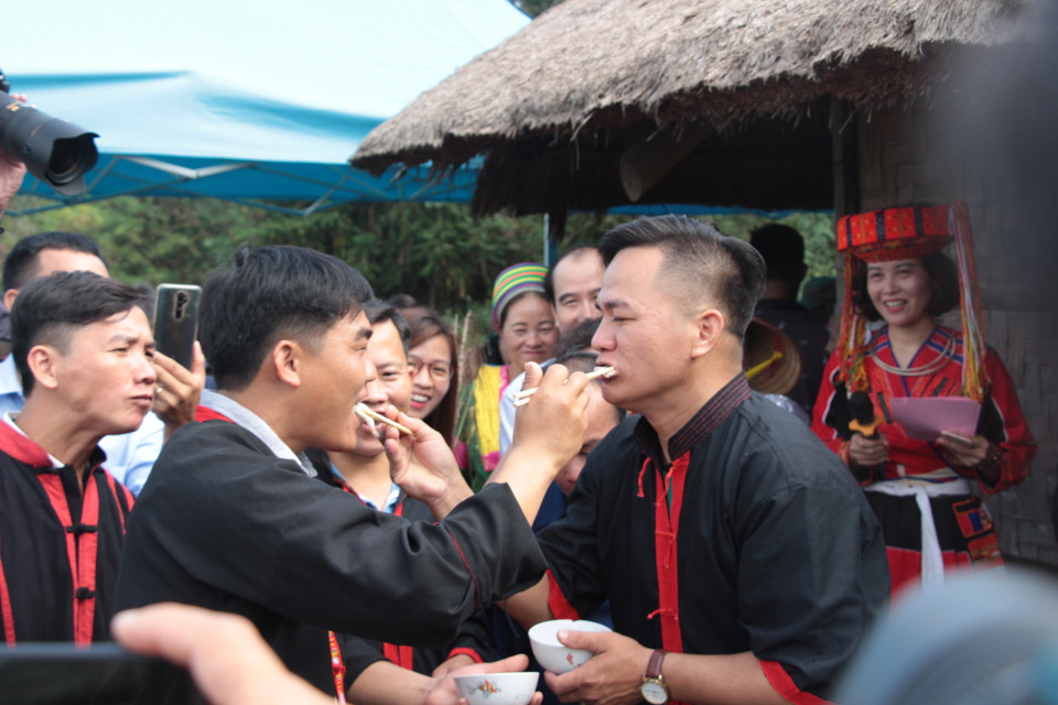 Phút vui đùa, ngẫu hứng khi hai người đoàn nhà nam gắp cho nhau những miếng thịt luộc được chuẩn bị sẵn trên mâm cúng. Theo quan niệm ngày xưa, sau lễ lạy thần xong thì quan làng dẫn những người trong nhà trai và anh em bên nội ra khỏi nhà để tránh trước khi con dâu vào nhà. Họ cho rằng nếu bên nội không tránh lúc đó thì dâu về nhà mình về sau này sẽ coi khinh anh em bên nội. (Ảnh: Vũ Văn Mừng)