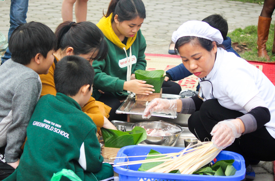 Với nhiều học sinh, đây là lần đầu tiên các em được tự tay gói bánh... (Ảnh: PV/Vietnam+)