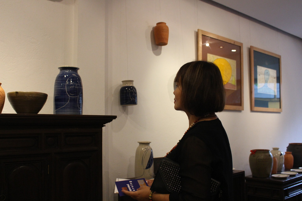 Với cái nhìn của một thi sỹ, chị Võ Thi Nhung chia sẻ rằng: ''Kinh Phật thường nói về sự trở về với đất và cát, gốm cũng hình thành, chắt lọc từ đất mẹ. Họa sỹ Thiết Cương viết kinh Phật lên gốm gợi cho tôi về điểm khởi đầu, giống như đưa chúng ta trở về với cát bụi.'' (Ảnh: Minh Anh/Vietnam+)