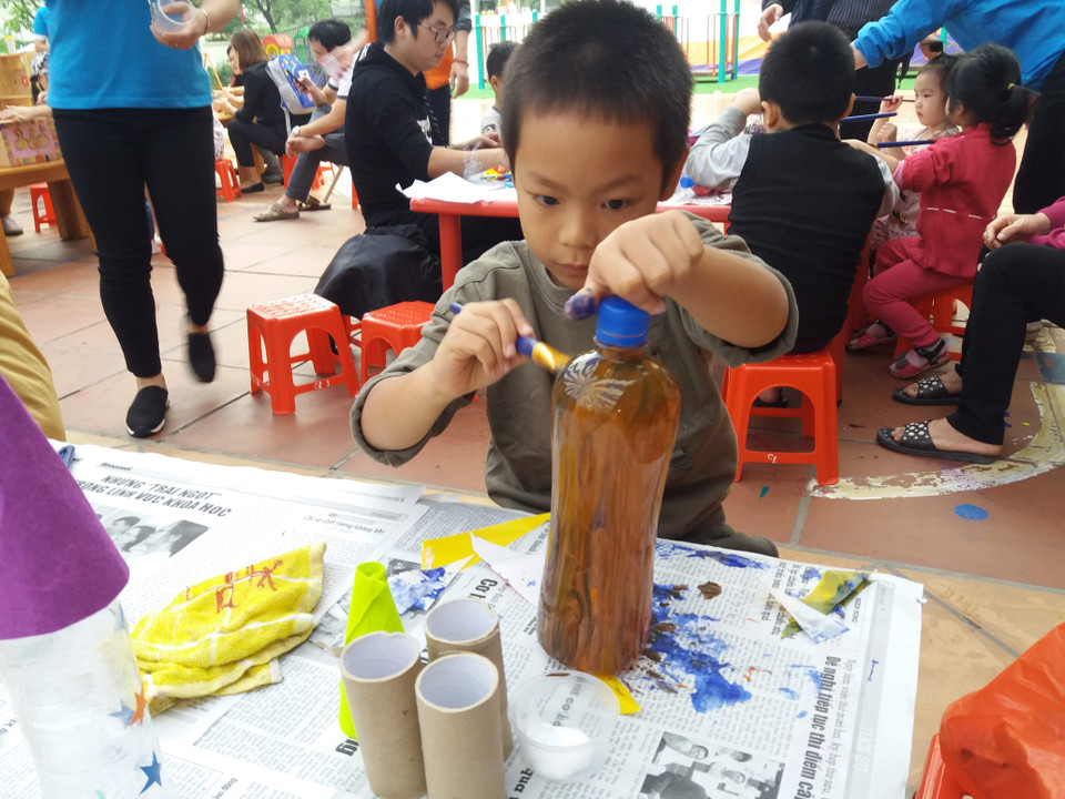 Một học sinh chăm chú trang trí cho lọ hoa làm từ vỏ chai. (Ảnh: PM/Vietnam+)