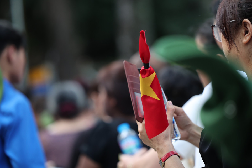 Nhiều bạn trẻ mang theo cờ rủ, lặng lẽ xếp hàng. (Ảnh: Minh Sơn/Vietnam+)