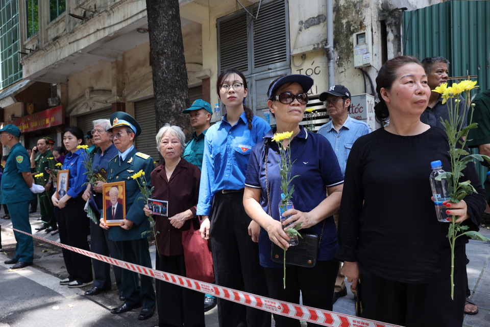 Hội Phụ nữ, Hội Cựu chiến binh phường Phạm Đình Hồ có mặt từ lúc 12h. Trên tay mỗi người đều cầm 1 bông hoa cúc vàng và di ảnh Tổng Bí thư. (Ảnh: Minh Sơn/Vietnam+)