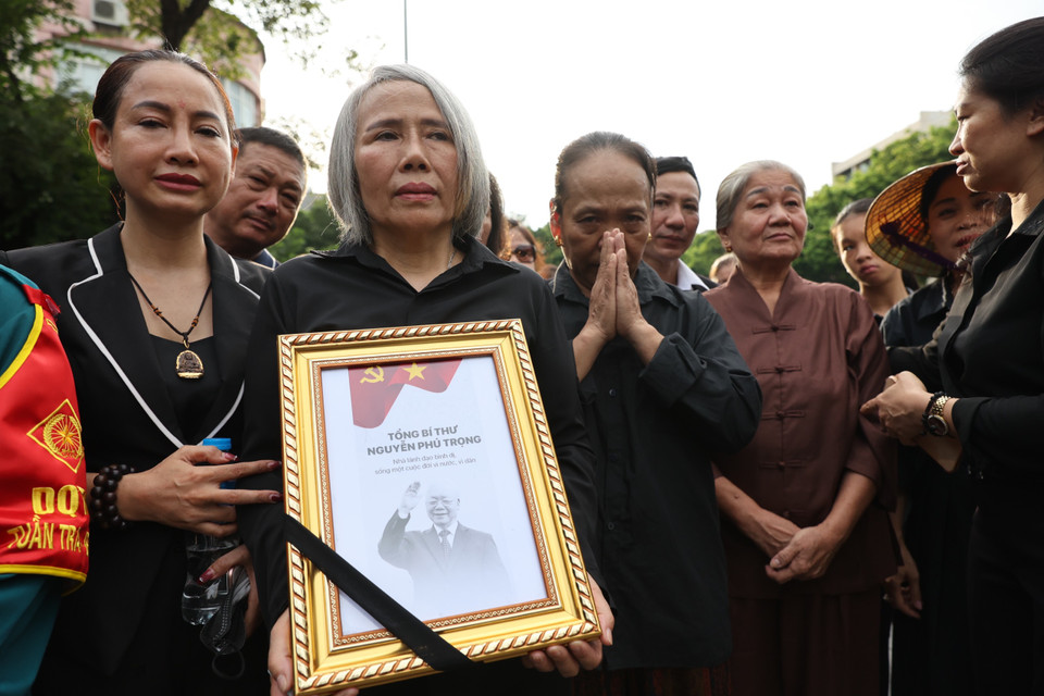 Bà Trần Thị Hậu sinh năm 1969 ở huyện Hoài Đức, Hà Nội, đã đưa các cháu mình đến xếp hàng từ 11h trưa nhưng do trời mưa nên bà đưa cháu về. Bà quay lại lúc 16h chiều để được vào viếng Tổng Bí thư. (Ảnh: Minh Sơn/Vietnam+)