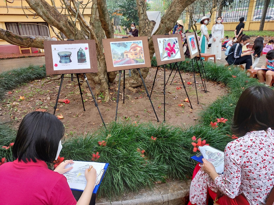 Khách tham quan có thể chọn mẫu để ký họa hoặc tô màu, ghi lại những hình ảnh đáng nhớ của hoa gạo tháng Ba và kiến trúc của Bảo tàng Lịch sử Quốc gia. (Ảnh: Minh Thu/Vietnam+)