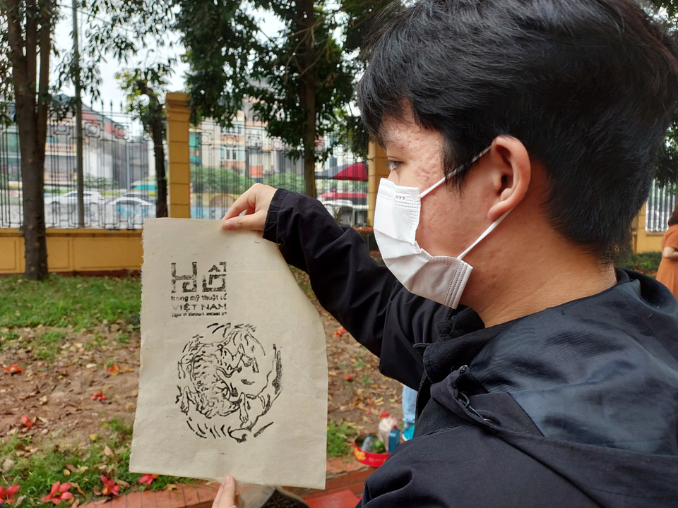 Một bạn trẻ vừa hoàn thành bản in tranh hổ trên giấy dó. (Ảnh: Minh Thu/Vietnam+)